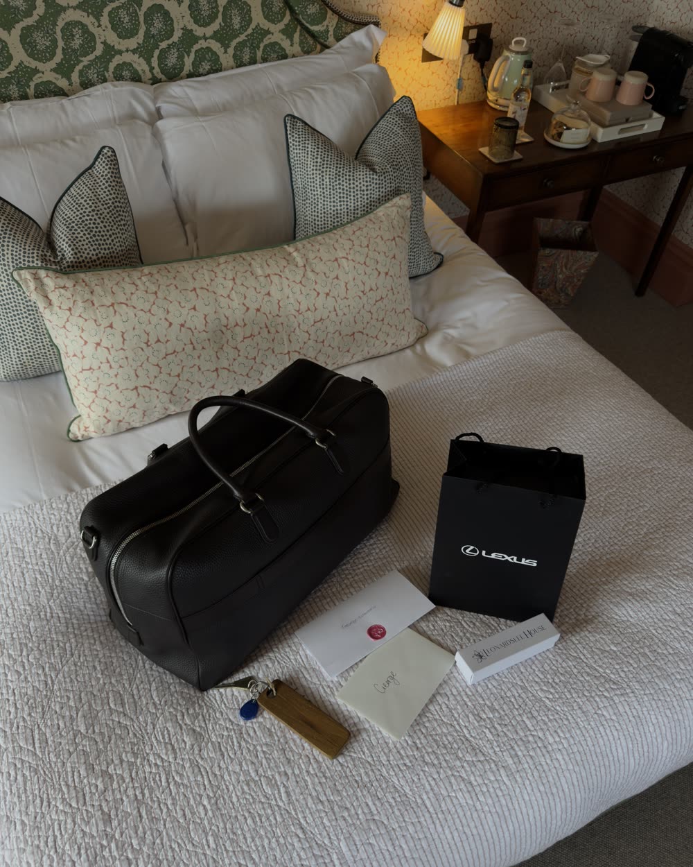 Leather holdall and turndown items laid out on a hotel bed